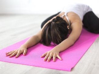 Devojka radi jogu na prostirci.