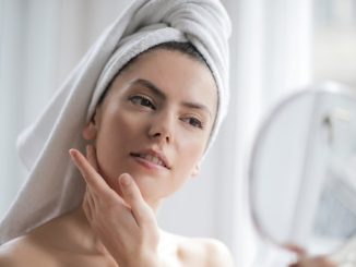 Žena sa peškirom na glavi se gleda u ogledalu