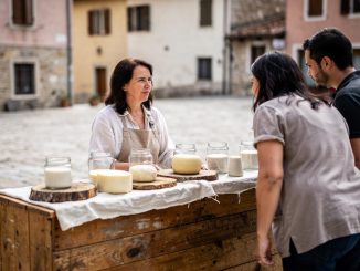 Prodavačica na otvorenom prodaje sireve i tegle mlečnih proizvoda u razgovoru sa kupcima